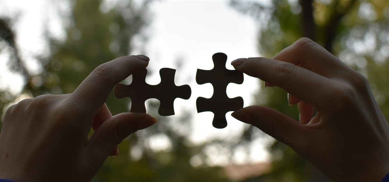 close up of hands holding two jigsaw pieces