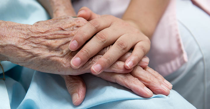 A nurse holds the hand of an elderly patient