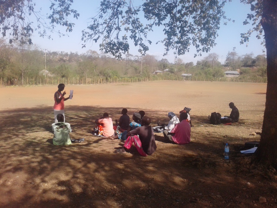A community facilitator running a parenting group under a tree in Bondo, Kenya