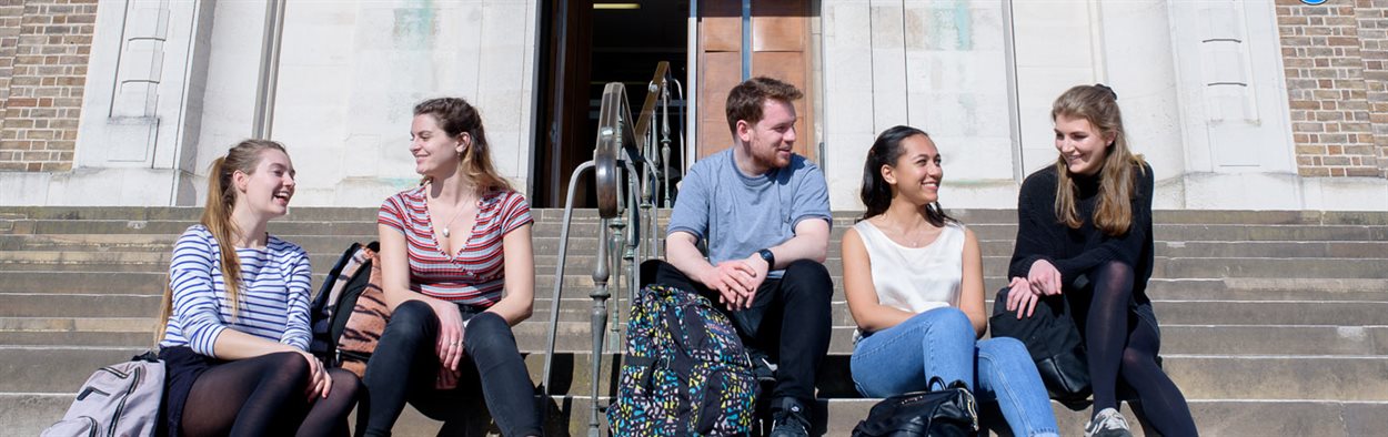 Four female and one male student sitting outside the medical school