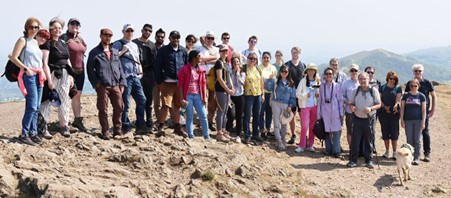 Group of people standing on a hill in hiking gear posing for the camera