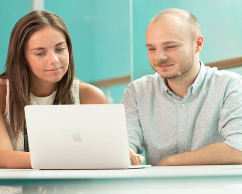 Female and male staff members at a laptop