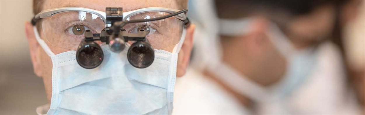 Male dental student looking at the camera with face mask and magnifying glasses