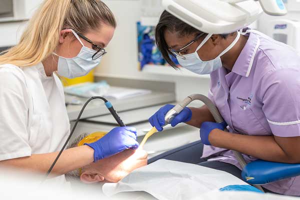 Female dental student inspecting a patient's mouth