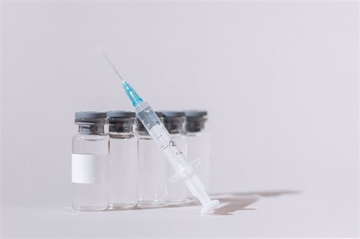 Syringe leaning on five small glass bottles