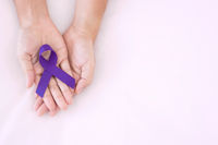 Hands holding a purple awareness ribbon