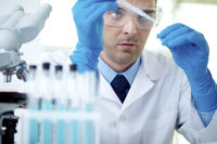 man in lab coat and goggles using a pipette and test tube in a laboratory