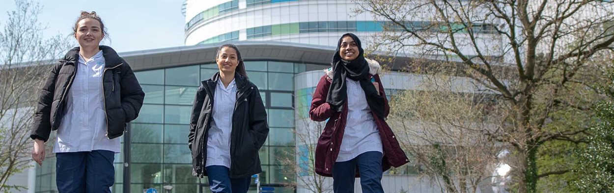 Three female students outside walking away from the Queen Elizabeth hospital