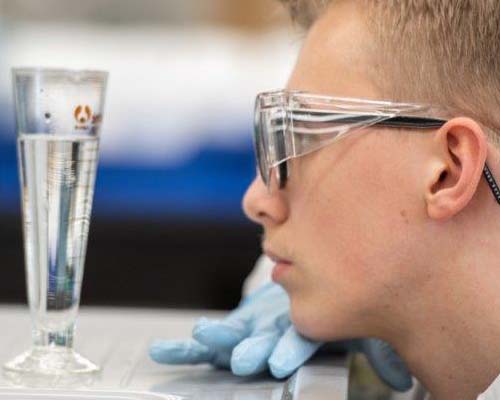 Male pharmacy student looking at liquid in a flask in a lab
