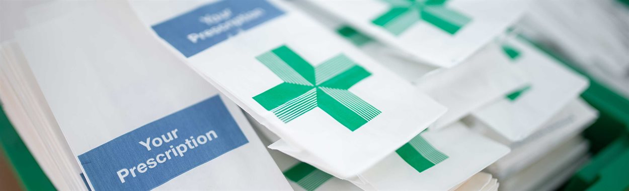 Pharmacy medication paper bags in a green tray