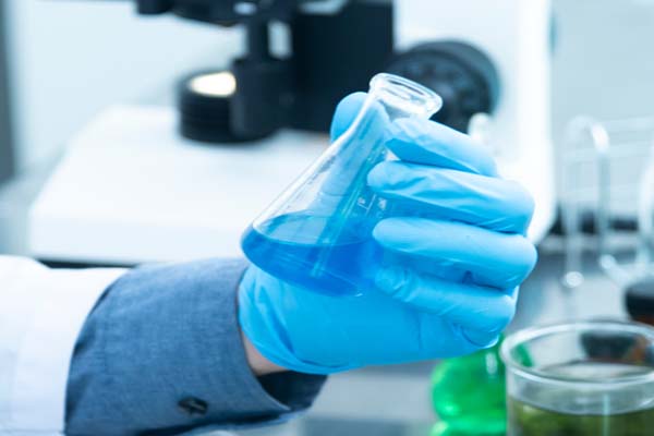 Lab worker holding liquid in blue beaker