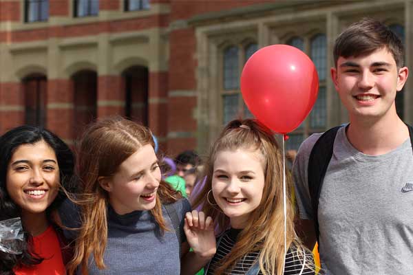 Three female students and one male student with a balloon