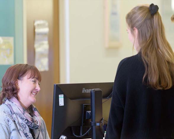 Female student speaking to female student support staff member over the student support desk