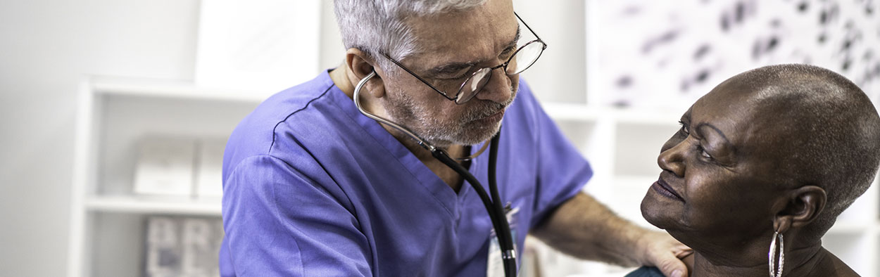 Male Doctor checking heart beat of female patient with sethoscope