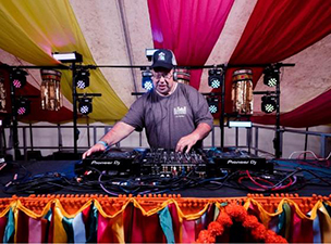 A man DJ-ing in a colourful tent.