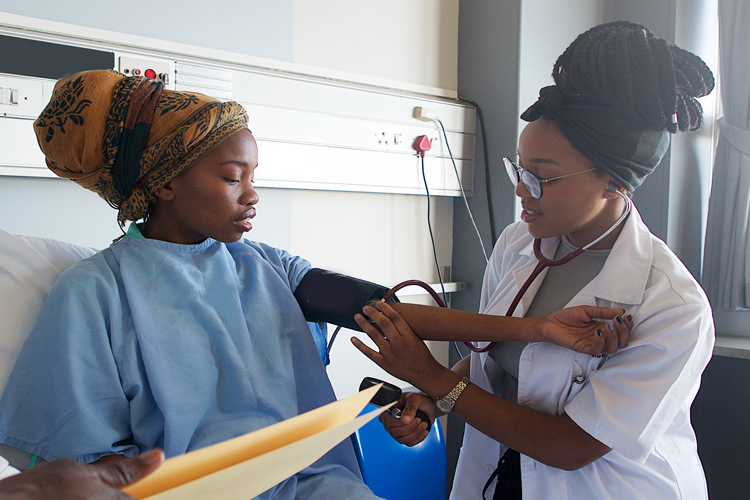 African woman in hospital getting her blood pressure checked by a female African Doctor