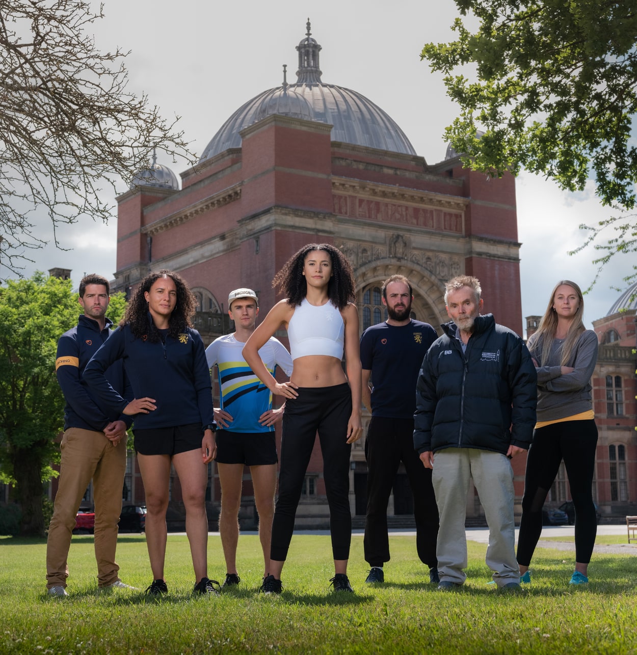 A group of the University of Birmingham's athletics talent from past and present standing in front of the Aston Webb building