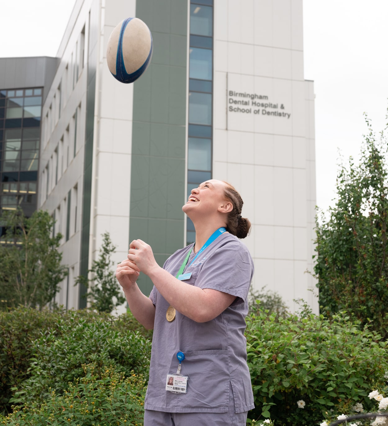 Laura Keates throwing a rugby ball in the air outside the University of Birmingham's School of Dentistry