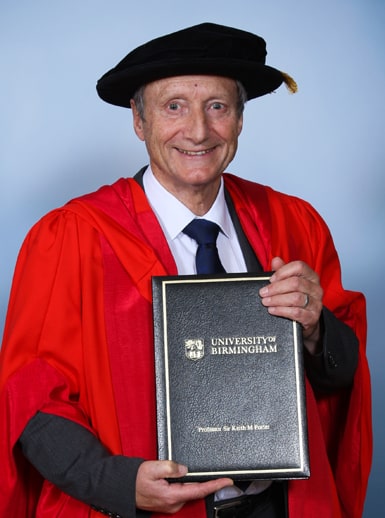 Professor Sir Keith Porter dressed in graduation gown and tam, holding his honorary degree