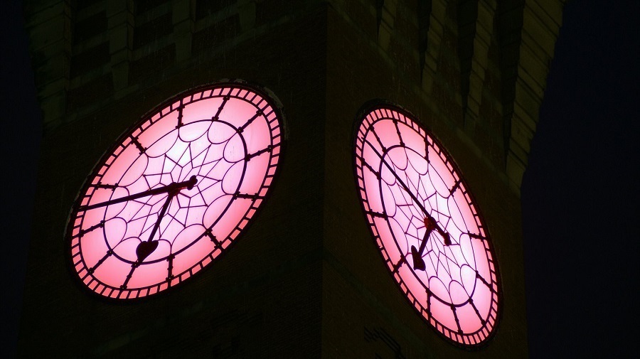 Close of up of Old Joe's clock face which is lit up in a warm pink colour
