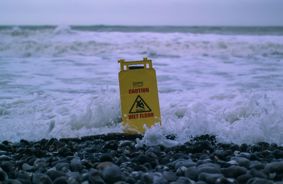A yellow warning sign on the shoreline