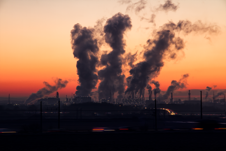 Industrial chimneys belching smoke against a red sunset