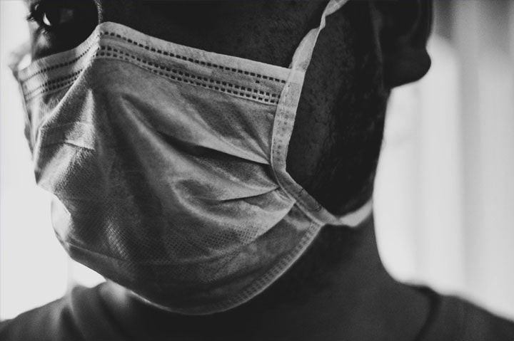 Close-up black and white photo of a man wearing a face mask.