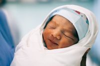 Newborn baby swaddled in a white blanket.