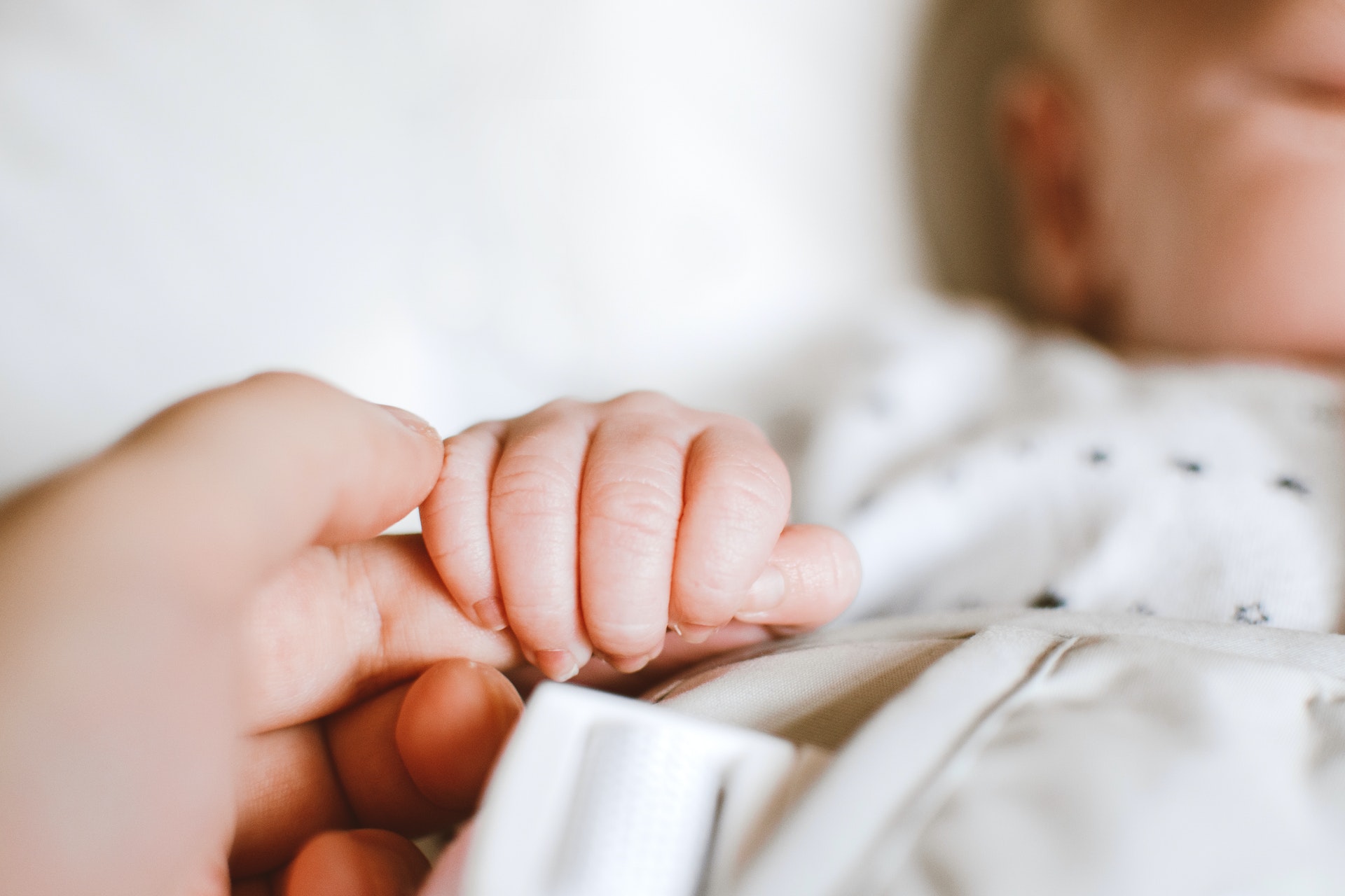 Person (out of shot) holding a babies hand