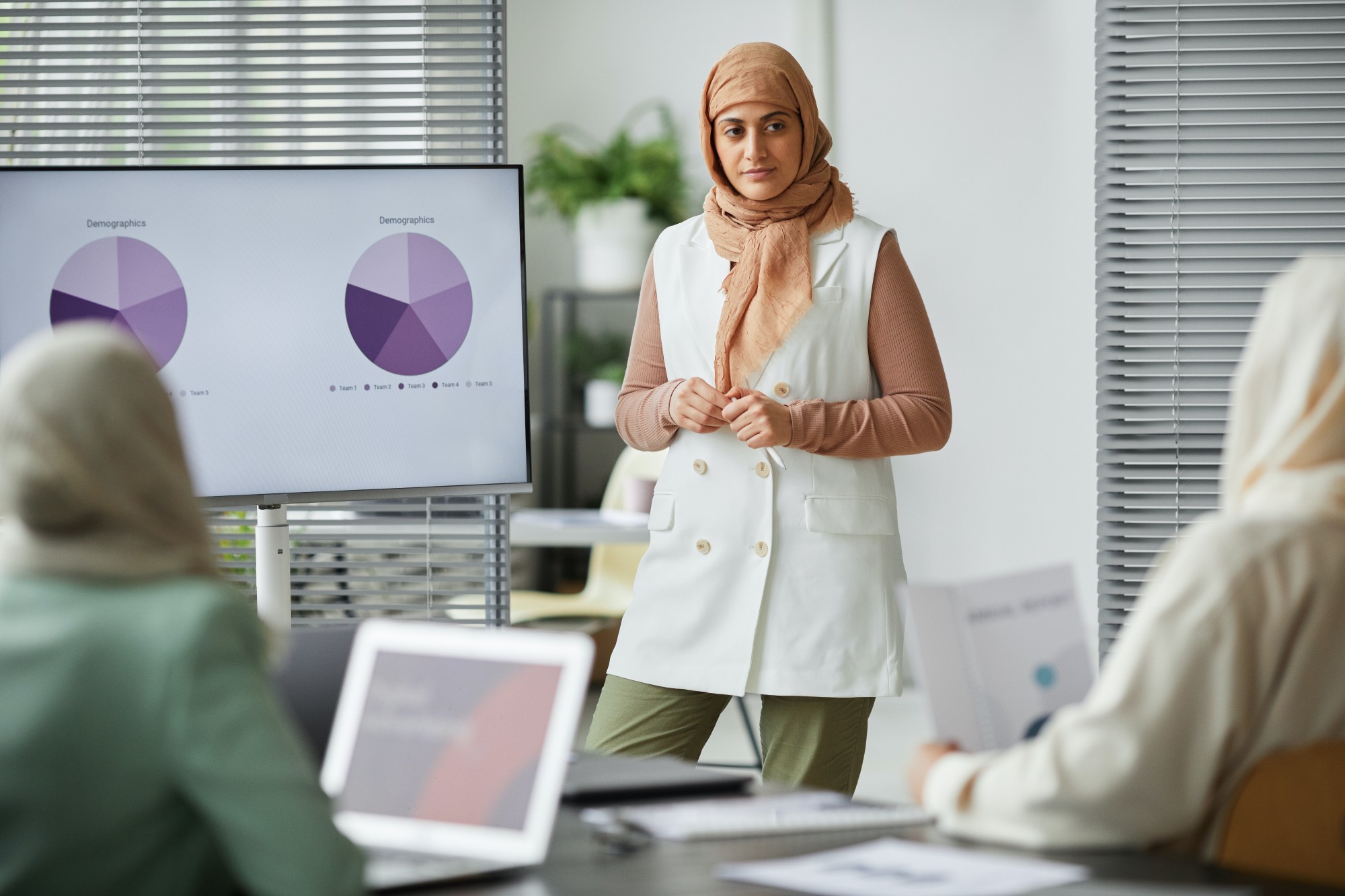 Muslim woman wearing a hijab, presenting to a room of other Muslim women.