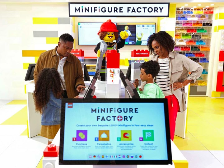 A family with two young children using the LEGO Minifigure Factory