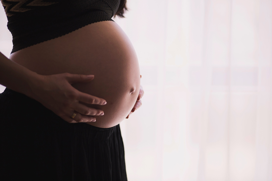 A pregnant women tenderly holds her stomach