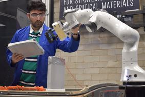 Researcher works with car battery and robotic arm