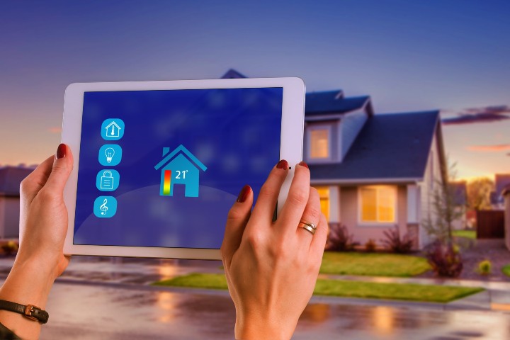 hands holding a tablet in front of a house
