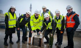 Wearing hi-vis vests and hard hats, Professor Andy Schofield, Director of Estates Trevor Payne, Willmott Dixon's Senior Project Lead Russell Hall, and Associated Architects Director Warren Jukes stand on top of the new School of Engineering building for t