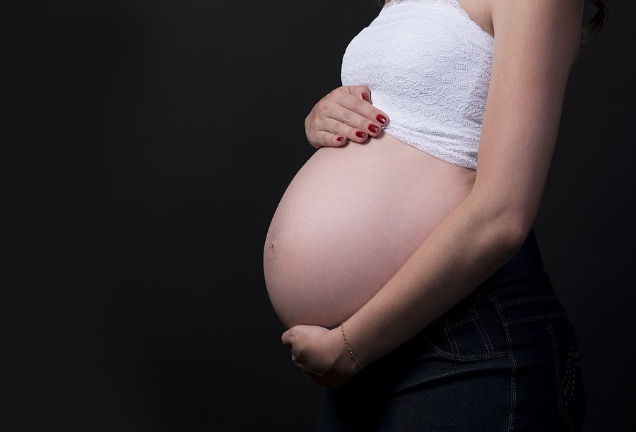 woman holding her bare pregnancy bump