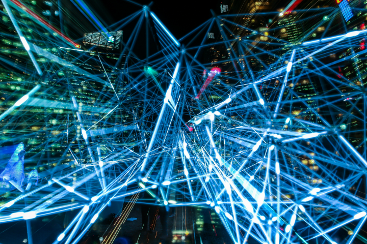 Time lapse photography of blue lights against the backdrop of a city at night.