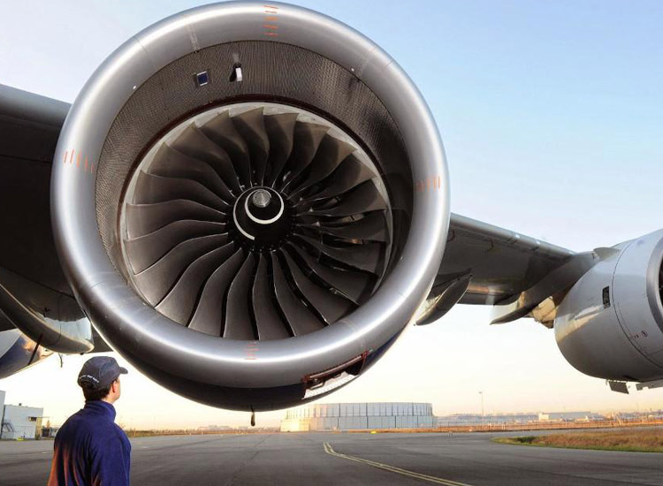 An engineer inspects a Rolls-Royce-manufactured jet engine on a plane