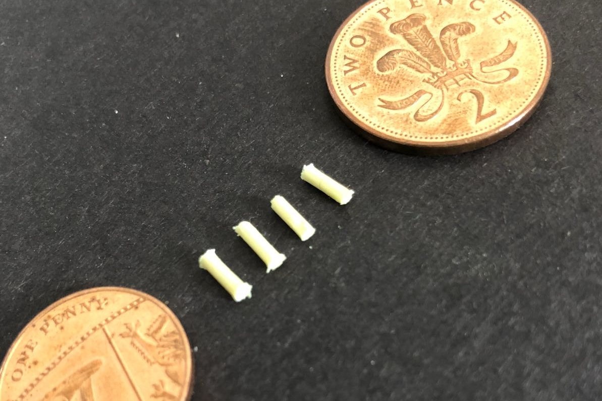 The brain implant device next to two two pence coins to show the small scale