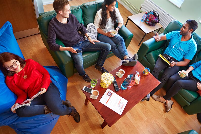 A group of students sitting in the social room chatting and reading