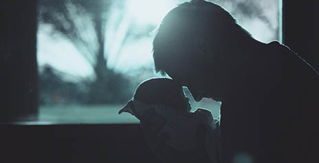 A father holding his baby silhouetted against a window