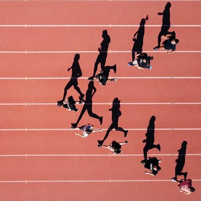Eight people race on a track in a triangular formation, taken from above.