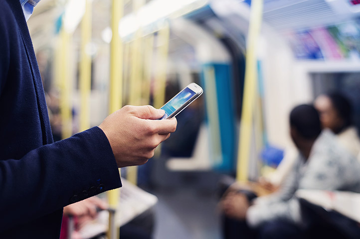 person looking at mobile phone whilst on the underground railway