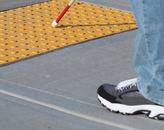 visually impaired person walking with a stick