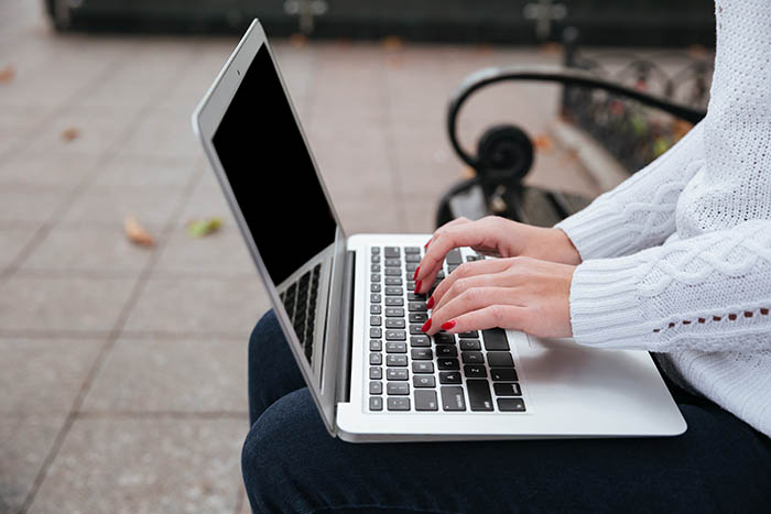 Person sitting outside on a bench working on a laptop