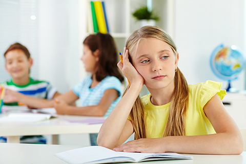 young girl in classroom day dreaming