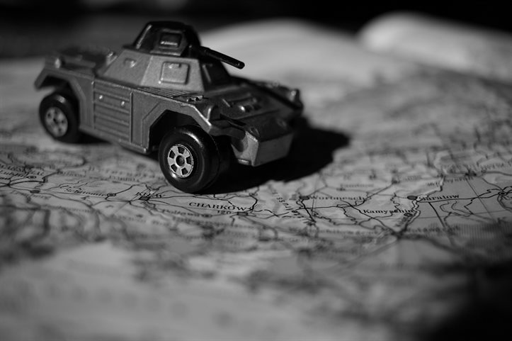 A monochrome image of a toy tank on a global map