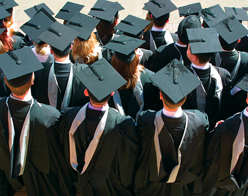 A back view of students graduating all wearing their caps