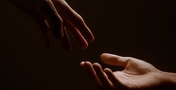 person reaching out to grasp another persons hand