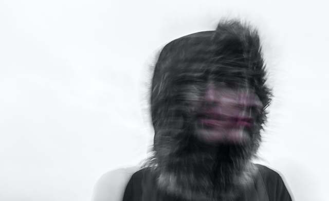 Blurred face of a young person in a winter coat and hood